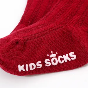 Detailed macro view of the white anti-slip silicone dots on a red cotton baby floor sock