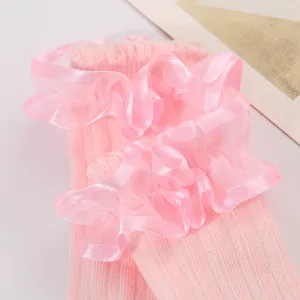 Detailed view of soft pink ruffle lace on baby girl princess mid-calf socks texture