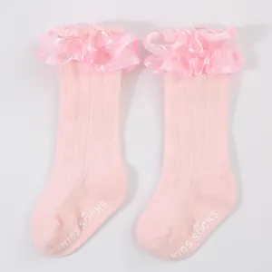 Detailed view of pink lace baby socks featuring anti-slip bottom with logo print.