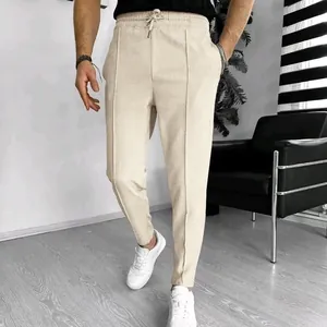 Close-up of men's beige waffle knit drawstring pants in a modern room setting