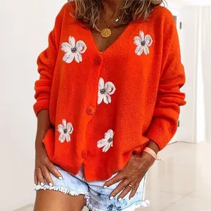 Dettaglio del cardigan in maglia arancione con delicati motivi floreali ricamati bianchi