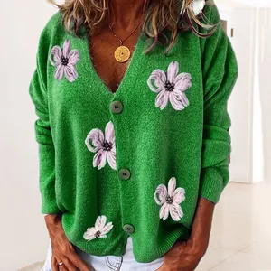Dettaglio di un elegante cardigan in maglia verde vintage con ricami di fiori viola.