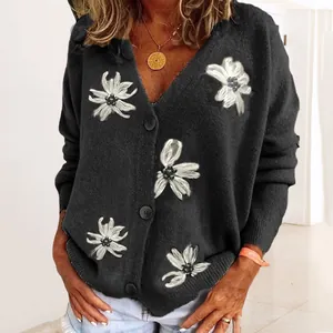 Primo piano del cardigan nero in maglia con eleganti ricami floreali bianchi in rilievo