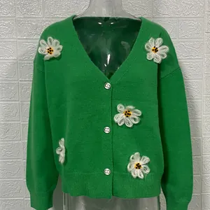 Vista dettagliata del cardigan in maglia verde con fiori bianchi ricamati in 3D