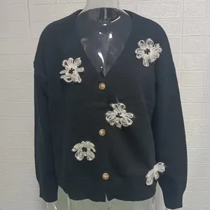 Dettaglio del cardigan in maglia nera con ricami floreali 3D e bottoni in stile vintage