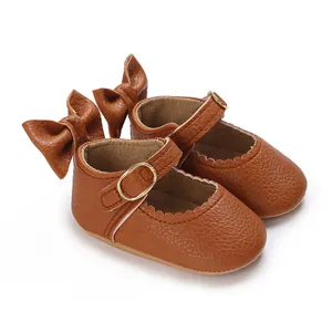 Close-up of brown baby Mary Jane shoes with back bows and scalloped edges.