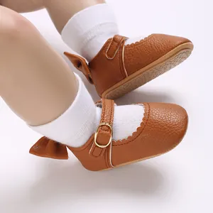 Close-up of brown baby girl pre-walker shoes featuring an elegant buckle and bow detail.