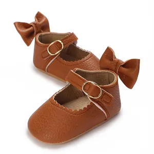 Close-up of brown faux leather baby shoes with decorative bows and gold buckles