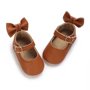 Detailed macro view of brown synthetic leather baby girl Mary Jane walking shoes with bow