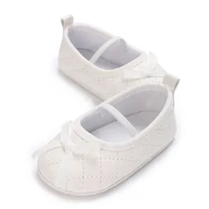 Close-up of white quilted baby Mary Jane shoes with delicate bow and elastic strap