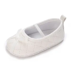 Close-up of white quilted baby princess shoes with bow detail and soft sole