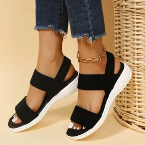 Primer plano de sandalias de cuña informales de tejido negro con tiras elásticas y suela.
