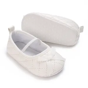 Detail view of white quilted baby shoes featuring anti-slip dotted sole and cute bow