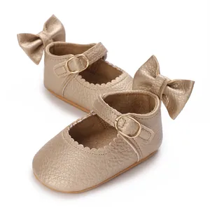 Macro view of champagne gold baby Mary Jane shoes with bow detail and leather texture