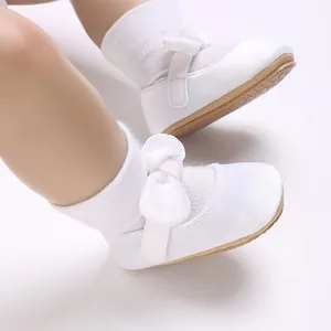 Close-up detail of white baby girl baptism shoes with soft bow and velcro strap