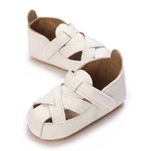 Dettaglio di scarpe primi passi per neonati con suola morbida e cinturini incrociati.