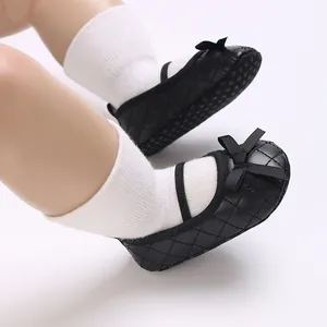 Detailed macro view of black quilted baby Mary Jane shoes featuring delicate bows