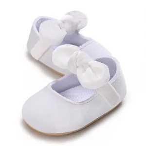 Close-up of white baby girl christening shoes with large satin bow details