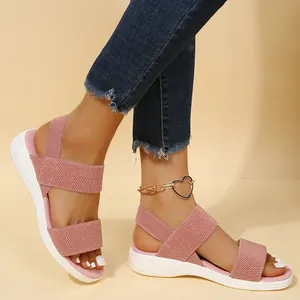 Detalle de sandalias de cuña de punto rosa con correas elásticas y suela blanca