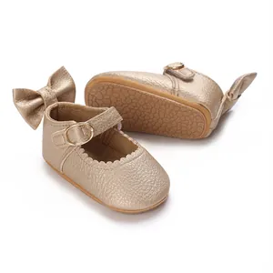 Detail view of champagne gold baby girl shoes with decorative bow and rubber sole