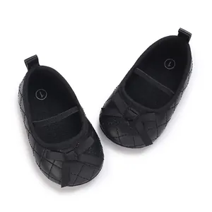 Close-up of black quilted baby flats featuring a ribbon bow and elastic ankle strap