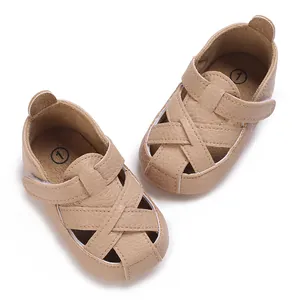 Primo piano di scarpine per neonati in ecopelle beige con suola morbida e design incrociato