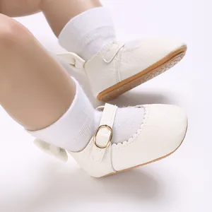 Close-up view of white baby girls Mary Jane shoes with bow detail and scalloped edges