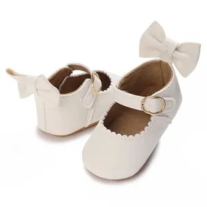 Close-up of elegant white baby girl walking shoes featuring a bow detail and golden buckle