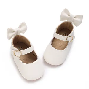 Detail view of cream white baby girl walking shoes with bow and gold buckle.