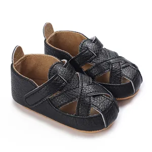 Dettaglio delle scarpe da passeggio nere intrecciate con suola morbida per bebè 0-1 anno