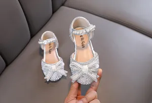 Vista detallada de zapatos de princesa plateados brillantes con lazo de purpurina y perlas