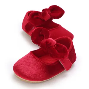 Detailed view of red velvet baby girl shoes featuring a large bow and soft sole.
