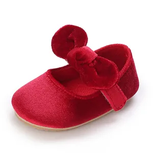 Close-up of red velvet baby girl shoes featuring a soft sole and a charming large bow accent.