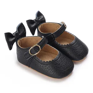 Detailed view of black leather baby girl Mary Jane shoes with bow and gold buckle.