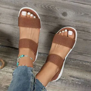 Detalle de sandalias con cuña y tiras elásticas marrones sobre fondo de madera