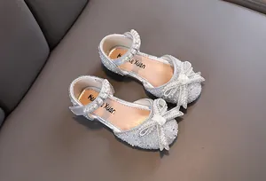 Primer plano de zapatos de princesa plateados para niña con diamantes de imitación y lazo
