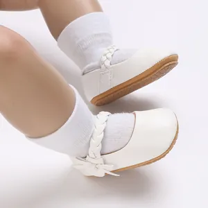 Detailaufnahme von weißen Baby-Mary-Janes mit geflochtenem Riemen und Gummisohle.