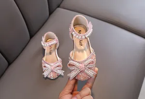 Detalle de zapatos de princesa rosas para niñas con lazo de perlas y brillantes de strass