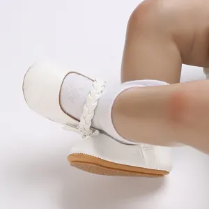 Nahaufnahme weißer Lauflernschuhe für Baby Mädchen mit geflochtenem Riemen und Gummisohle