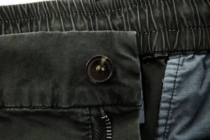 Close-up of the button closure and elastic waistband on men's dark olive cargo pants.