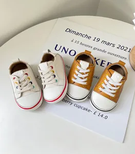 Detailansicht von cremefarbenen und braunen Baby-Lauflernschuhen mit bunten Ösen
