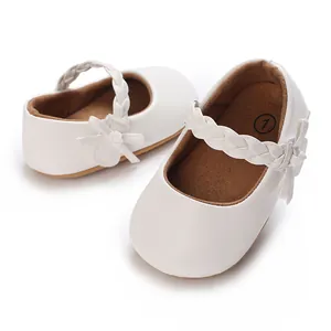 Detailansicht weißer Babyschuhe mit geflochtenem Riemen und Schleife für Mädchen.