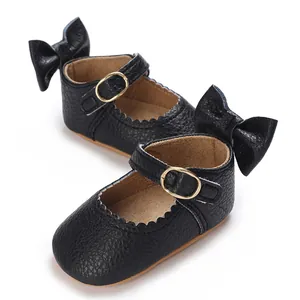 Detailed view of black baby girl shoes featuring a back bow and wavy scalloped edges.