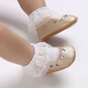 Detailed view of gold baby Mary Jane shoes with heart cutouts and white lace ruffles.