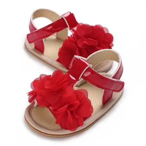Primer plano de sandalias de verano para bebé con flores de tela roja y suela blanda
