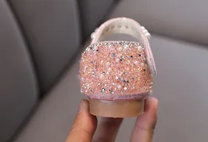 Primer plano de zapatos de princesa rosa para niñas con pedrería y perlas brillantes