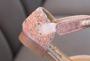 Primer plano detallado de los zapatos de princesa rosas para niñas con pedrería y perlas
