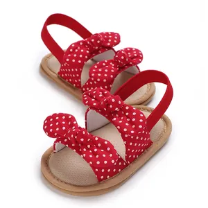 Primer plano de sandalias rojas con lunares para bebé con lazos decorativos y elásticos