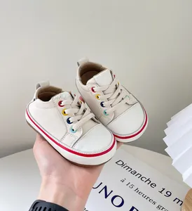 Nahaufnahme von Baby-Lauflernschuhen mit bunten Ösen und weichem Leder in Creme