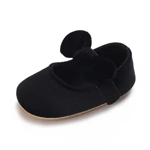 Detail view of black velvet baby girl baptism shoes with a large cute bow and soft sole.